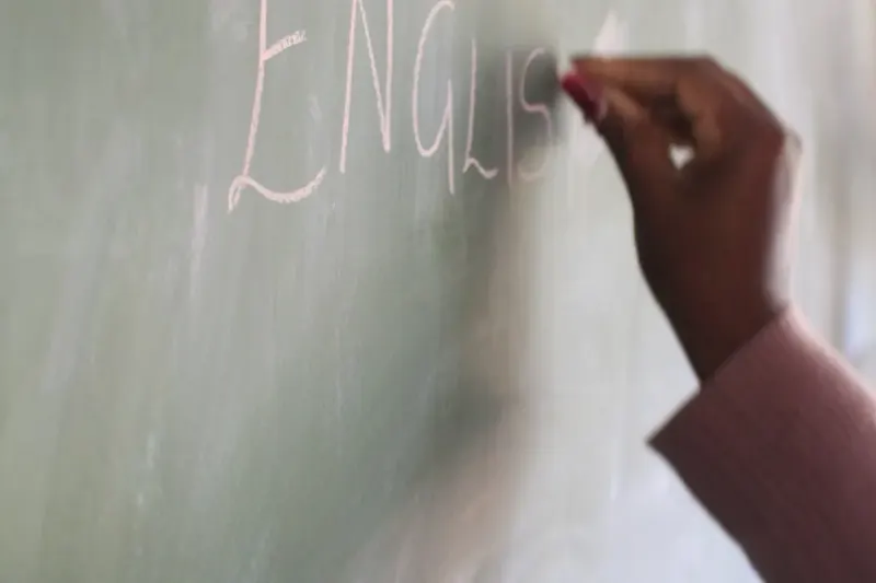 Преподаватель пишет слово English на доске